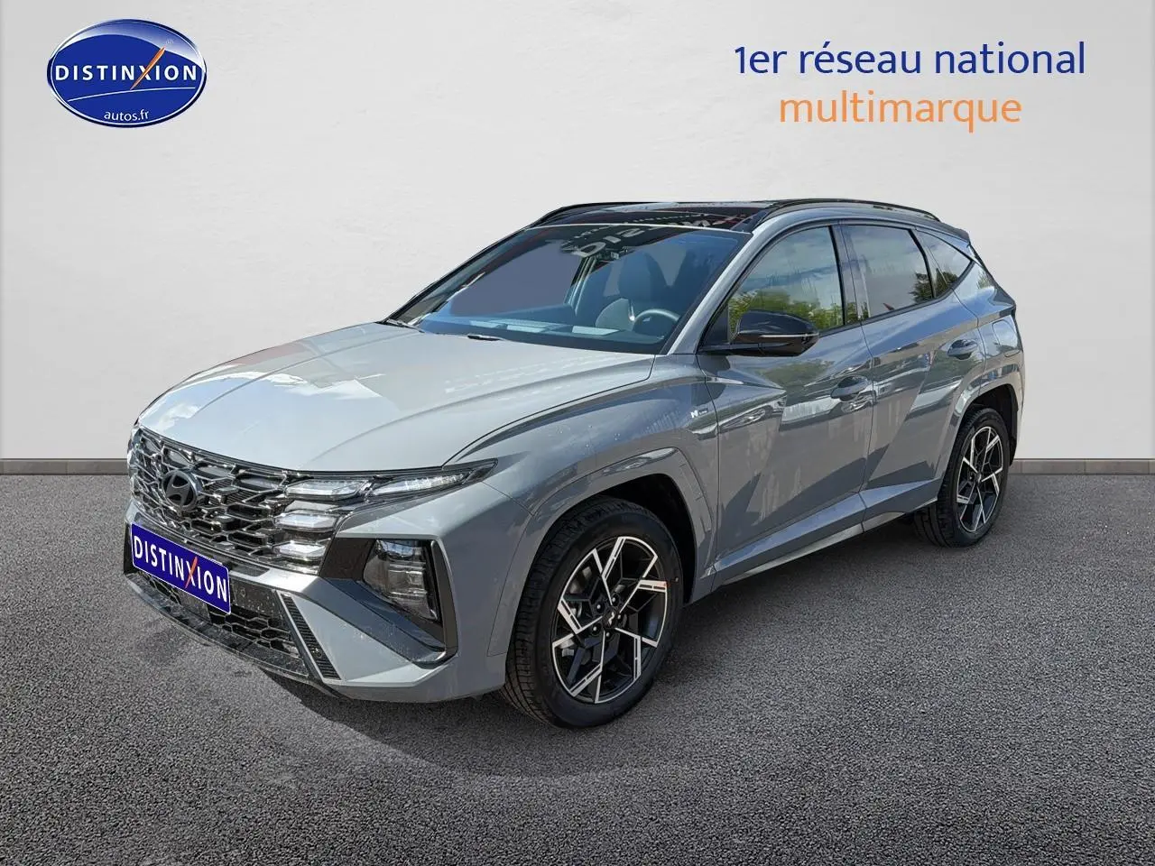 Hyundai Tucson gris shadow en 3/4 avant droit, avec calandre chromée et jantes alu distinctives.