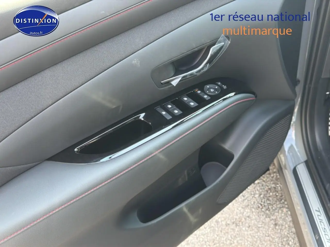 Gros plan sur la porte avant gauche grise du Hyundai Tucson 2026, avec commandes de vitres et habillage noir mat.