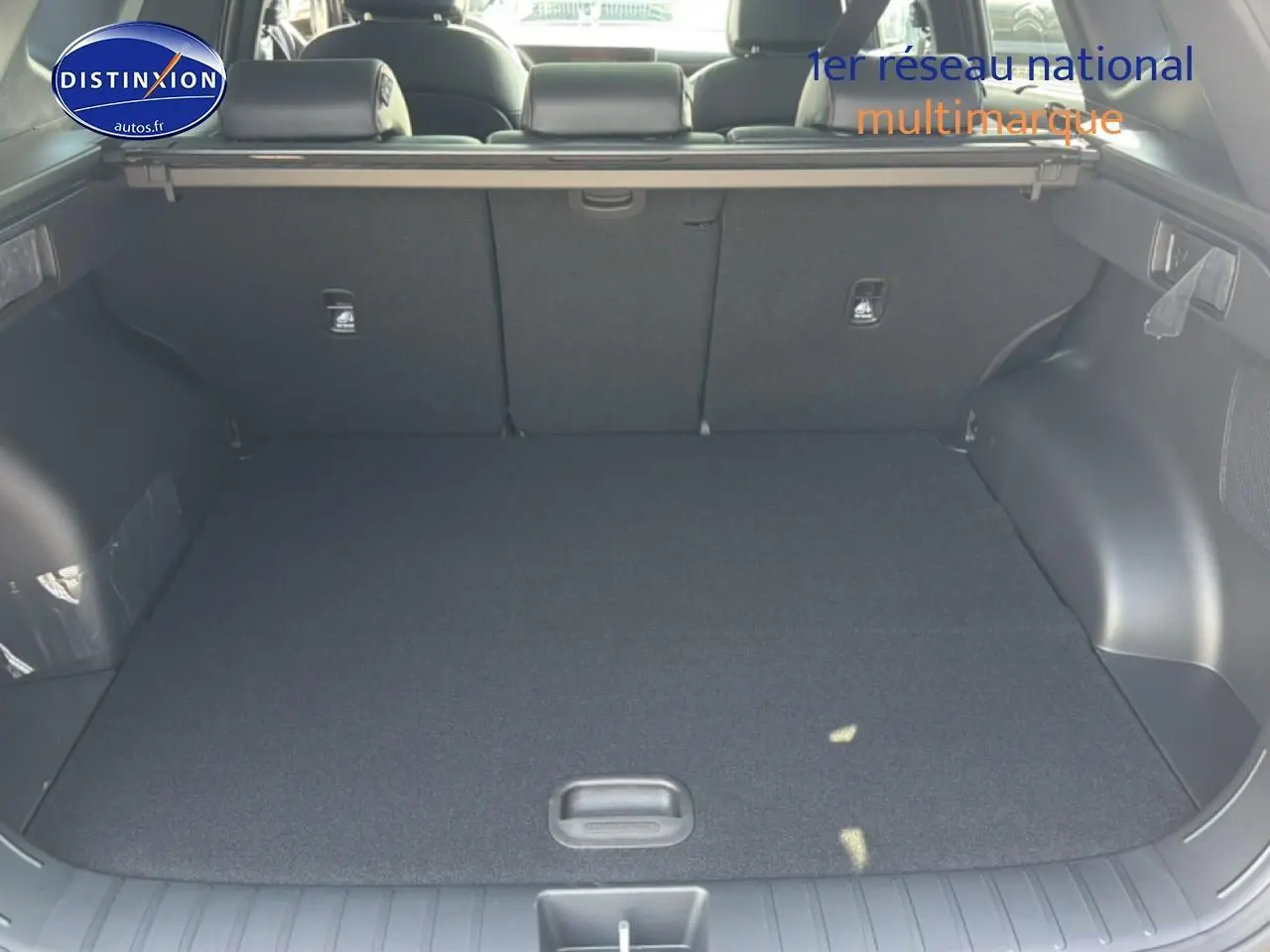 Coffre ouvert du Hyundai Tucson gris shadow, vue arrière montrant l'espace de chargement et la banquette rabattable.
