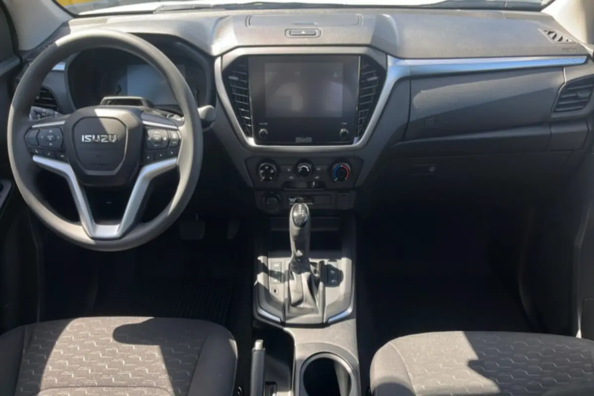 Vue intérieure frontale de l’Isuzu D-MAX 2026 avec tableau de bord noir, volant multifonctions et écran tactile central.
