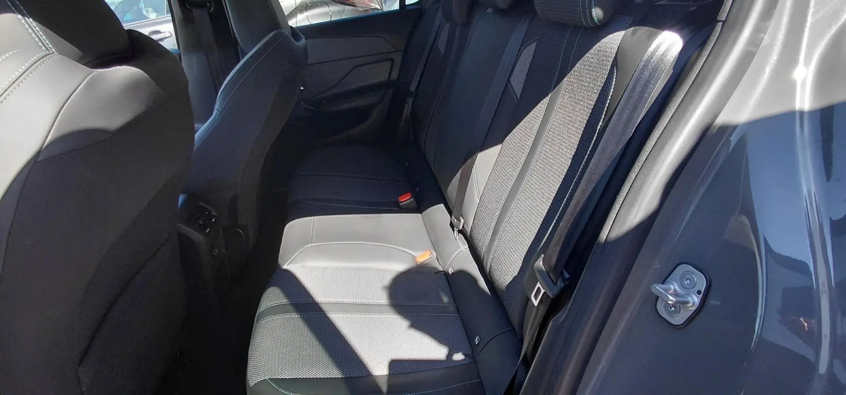 Vue intérieure côté droit des sièges arrière gris de la Peugeot 308 BlueHDi 130ch 2025 avec ceinture de sécurité visible.