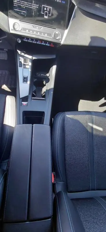 Vue plongeante sur la console centrale et siège avant gris foncé de la Peugeot 308 BlueHDi 130ch avec accoudoir central et écran tactile.
