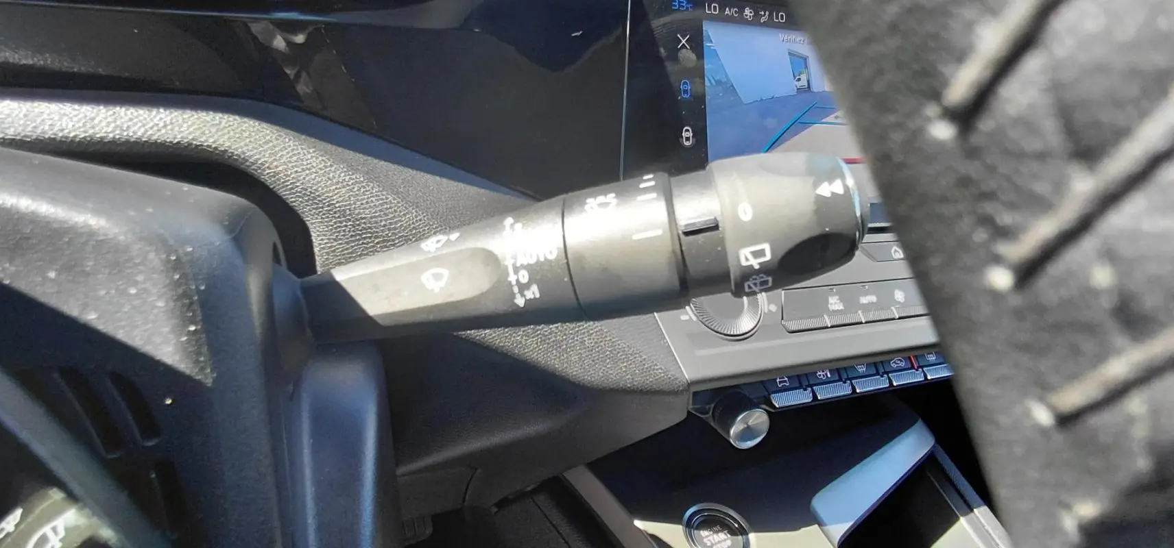 Gros plan sur la commande d’essuie-glace à gauche du volant dans l’habitacle d’une Peugeot 308 gris 2025.