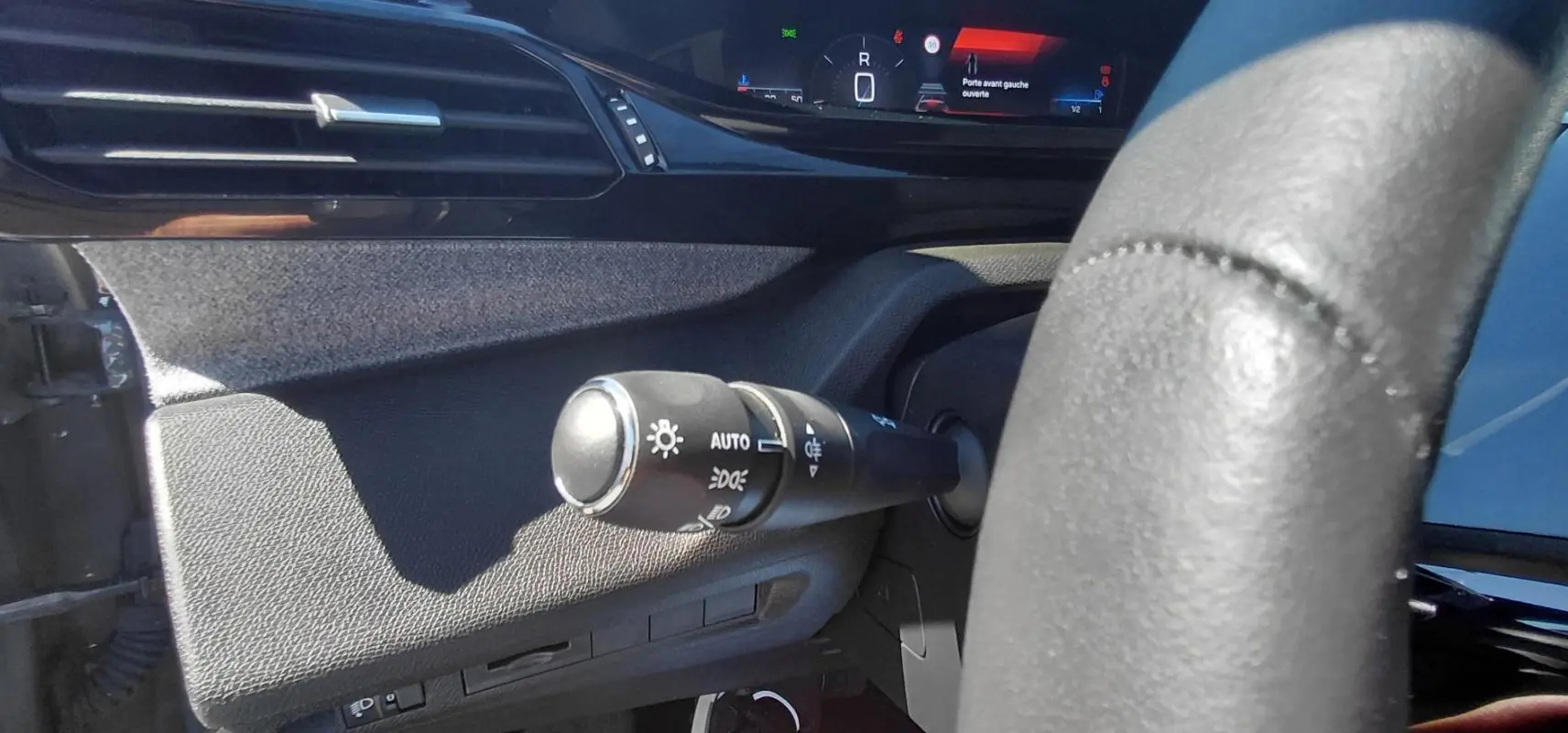 Gros plan sur la commande d’allumage automatique des feux côté gauche du tableau de bord d’une Peugeot 308 gris 2025.