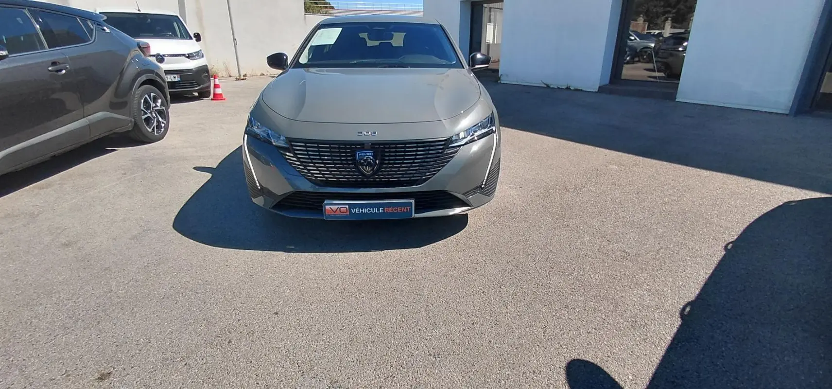Peugeot 308 gris vue de face, mettant en valeur sa calandre moderne et ses phares fins en extérieur.