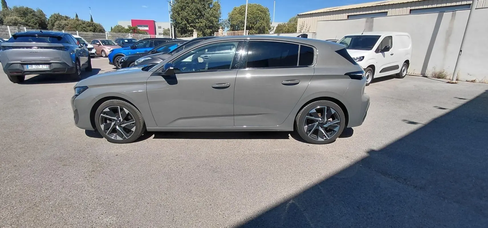 Peugeot 308 gris vue de profil côté gauche, avec jantes alliage et vitres teintées, stationnée en extérieur.