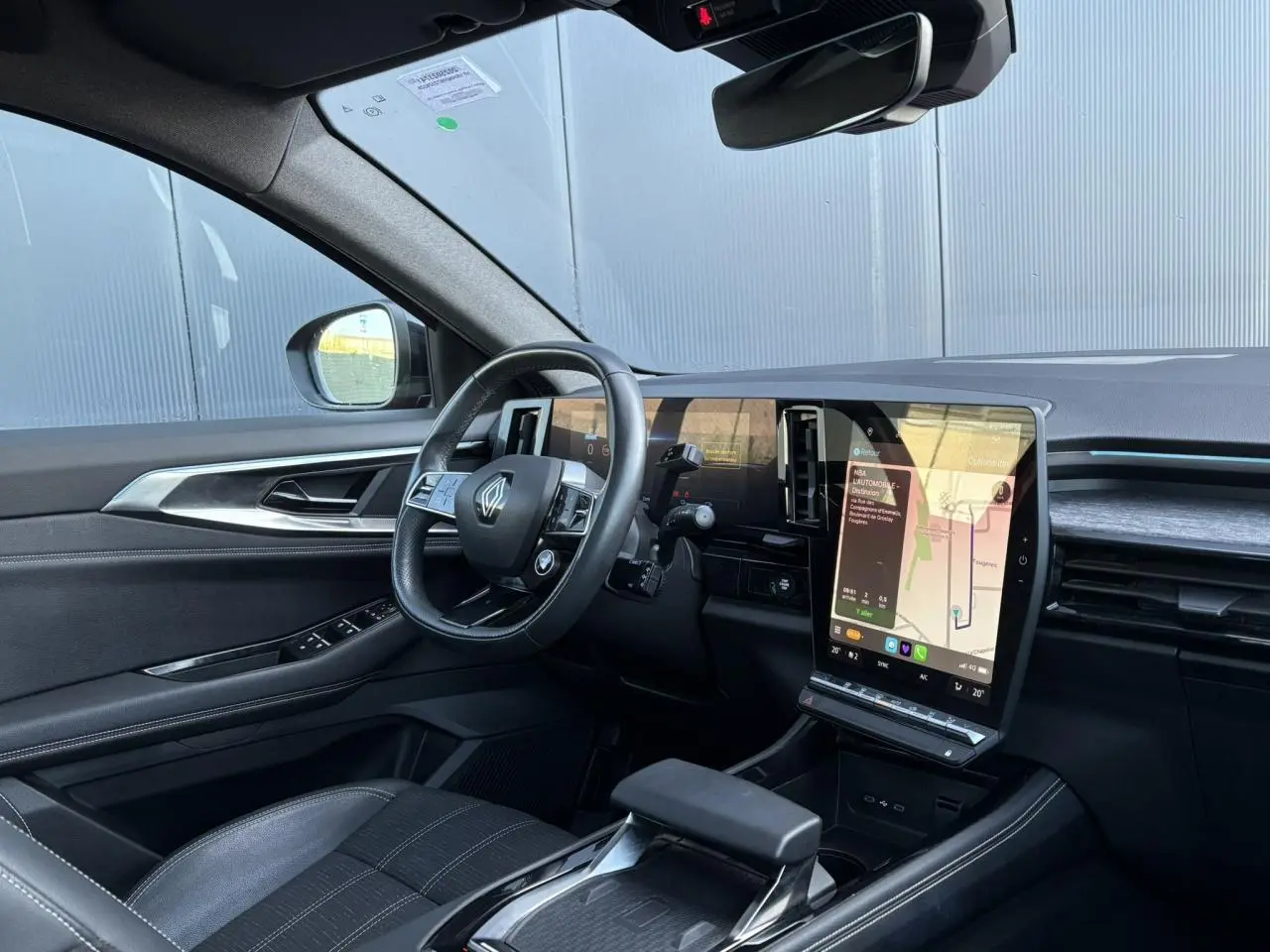 Intérieur côté conducteur du Renault Austral E-Tech 2024, volant cuir, écran tactile vertical et sellerie noire.