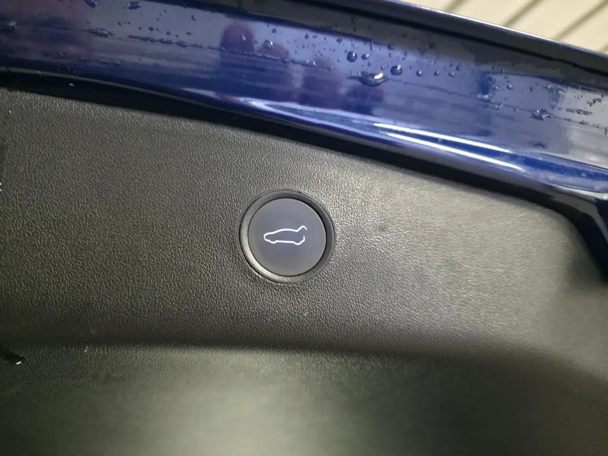 Bouton d'ouverture du coffre sur la partie intérieure du hayon bleu foncé d'une Tesla Model 3 RWD 2021.