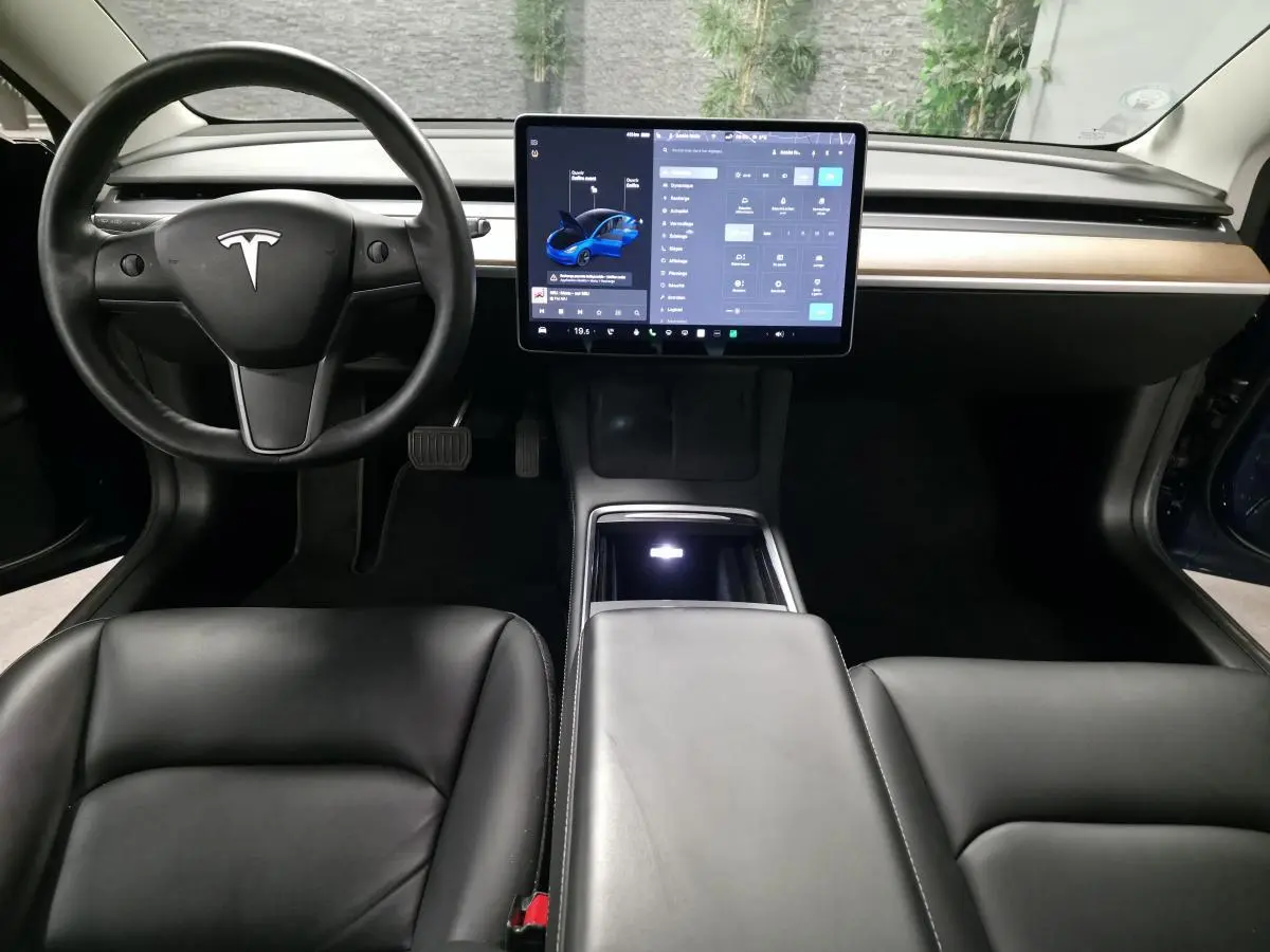 Intérieur noir de la Tesla Model 3 RWD 2021 avec tableau de bord minimaliste et grand écran tactile central.