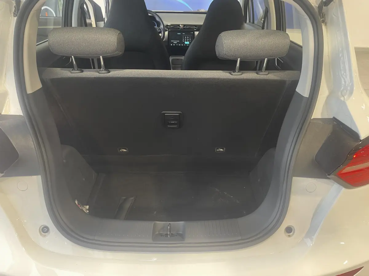 Vue arrière du coffre ouvert d'un LEAPMOTOR T03 Luxury blanc, montrant l'intérieur noir et les appuie-têtes arrière.