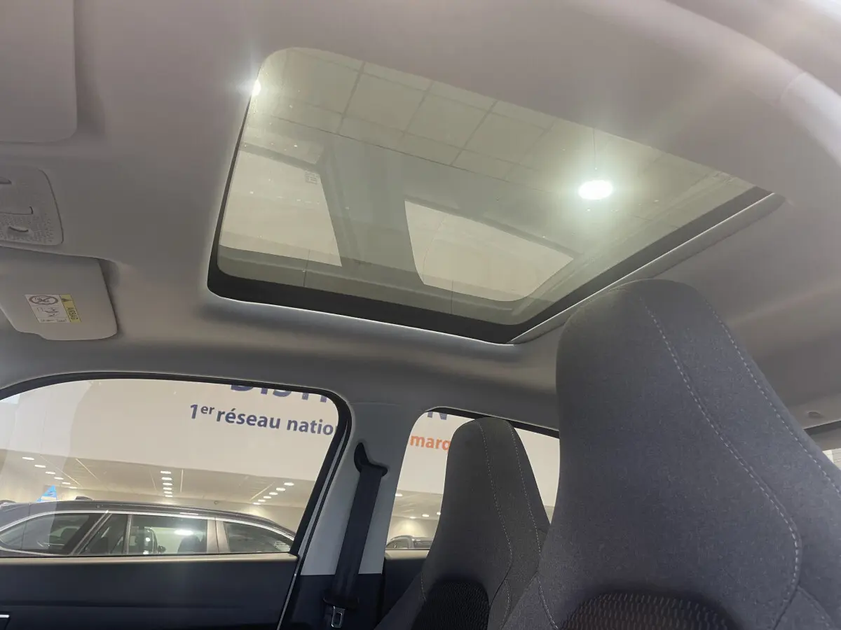 Vue intérieure du toit ouvrant panoramique et des sièges avant en tissu gris du LEAPMOTOR T03 Luxury blanc.