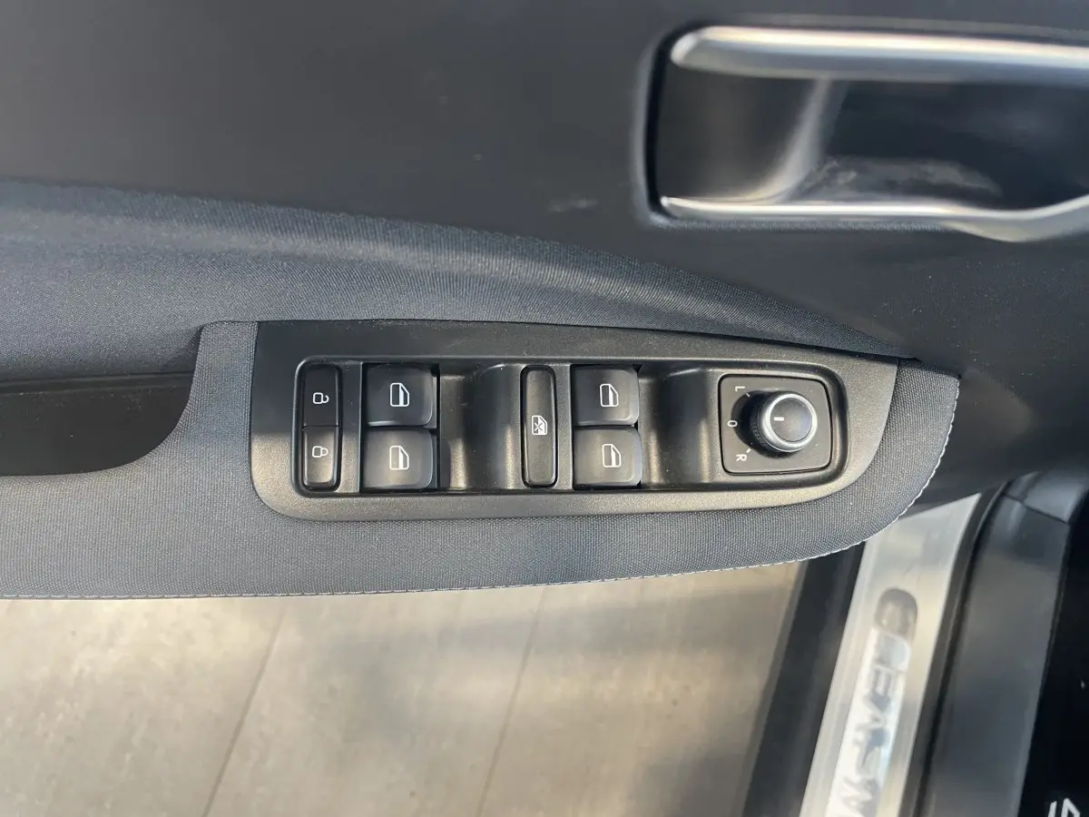 Gros plan sur les commandes de lève-vitres et rétroviseurs sur la porte côté conducteur d'une LEAPMOTOR T03 Luxury blanche.