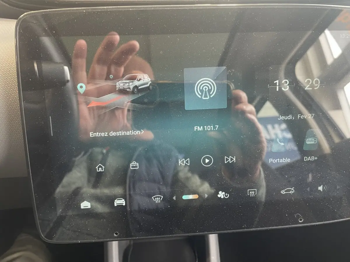 Écran tactile central du tableau de bord du Leapmotor T03 Luxury blanc, affichant la navigation et la radio FM.