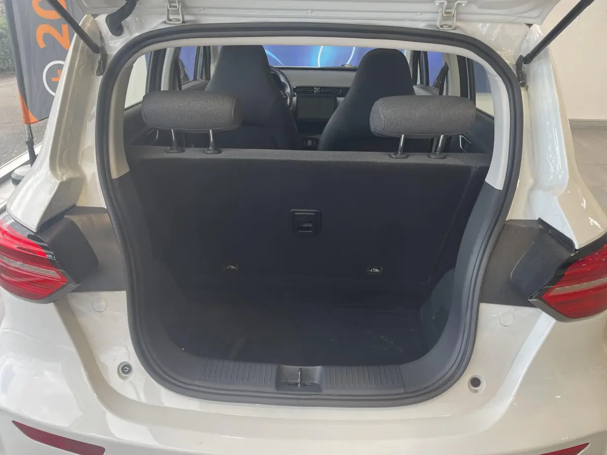 Vue arrière du coffre ouvert d'une LEAPMOTOR T03 Luxury blanche, montrant l'intérieur et les sièges avant.