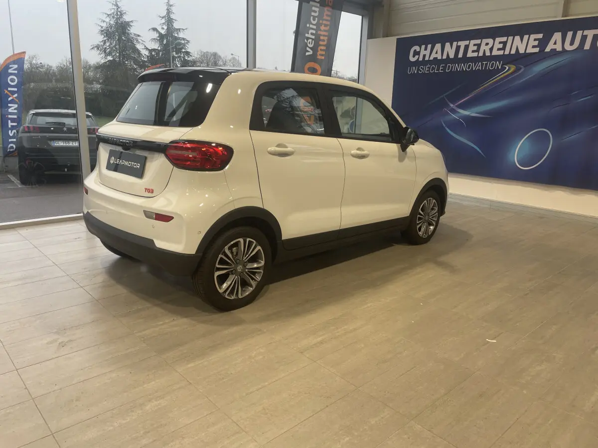 Vue 3/4 arrière droite du LEAPMOTOR T03 blanc, version Luxury, avec toit noir et jantes alliage en showroom.