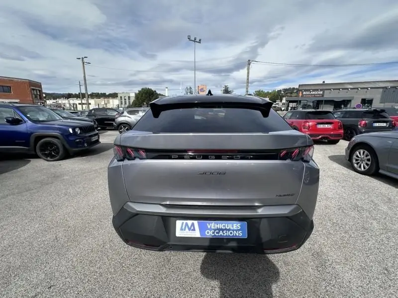 Vue arrière du Peugeot 3008 nouveau gris métal 2024 avec feux LED et logo Peugeot lumineux sur parking.