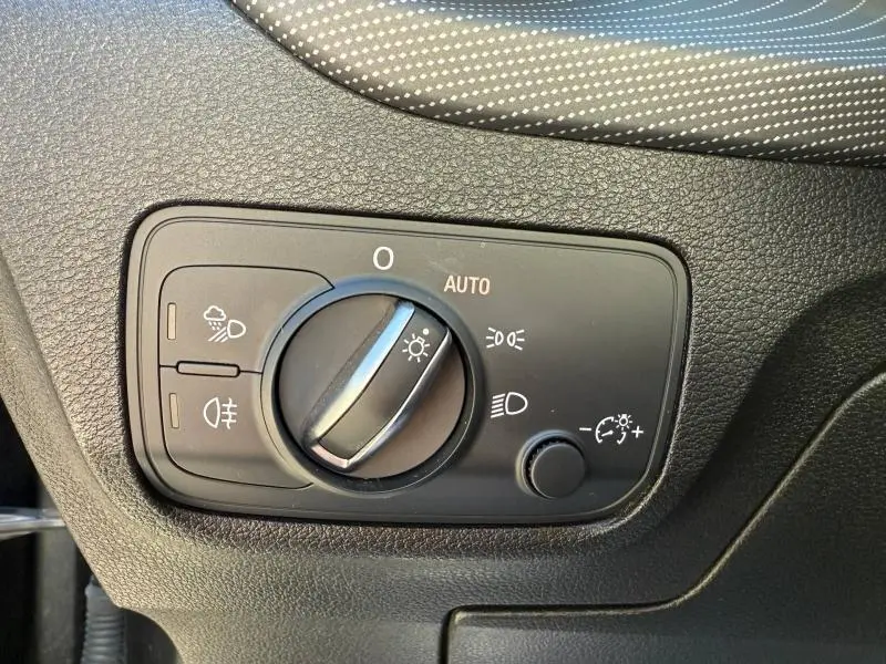 Gros plan sur le bouton de commande des phares dans l'habitacle de l'Audi Q2 35 TDI S line gris Daytona nacré, 2025.