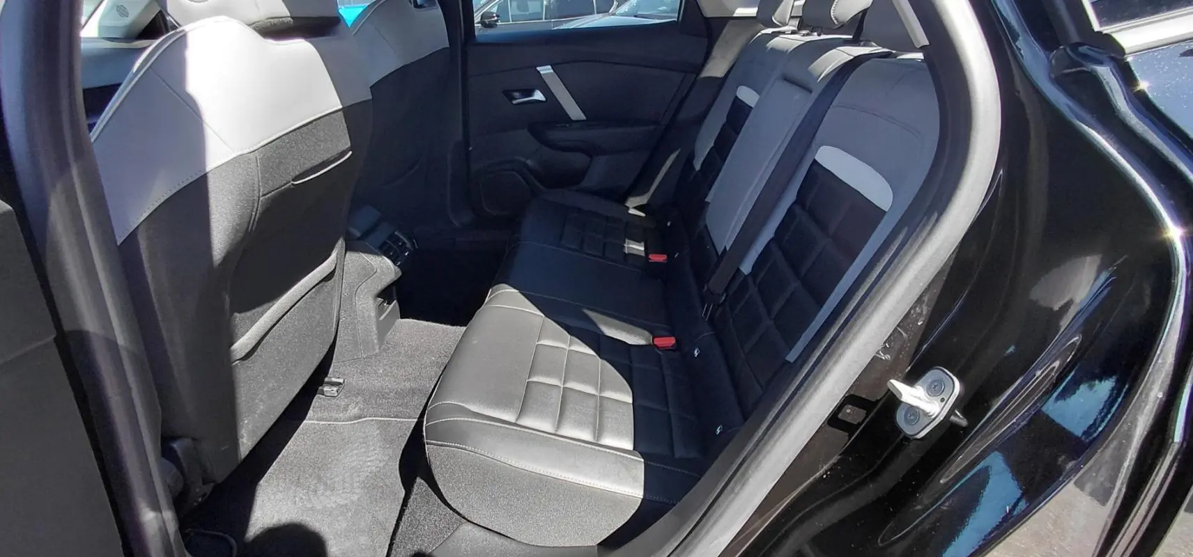 Vue intérieure côté droit des sièges arrière en cuir noir et gris du Citroën C4 X hybride 2025 avec porte ouverte.
