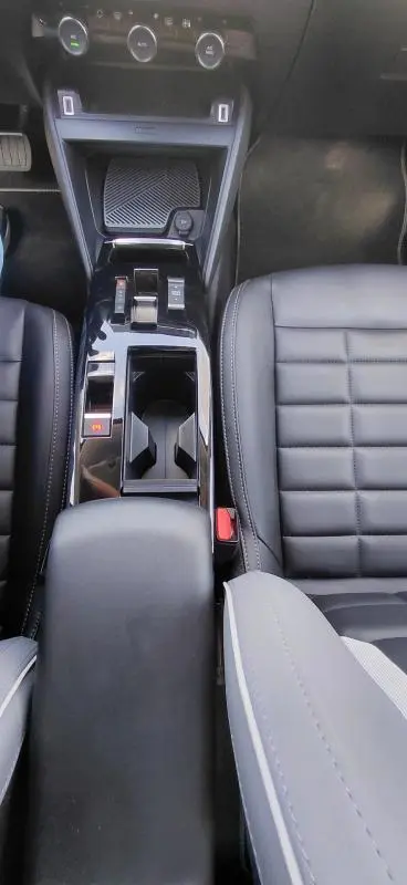 Vue plongeante de la console centrale noire du Citroën C4 X hybride 2025 avec accoudoir cuir et sièges en cuir noir.