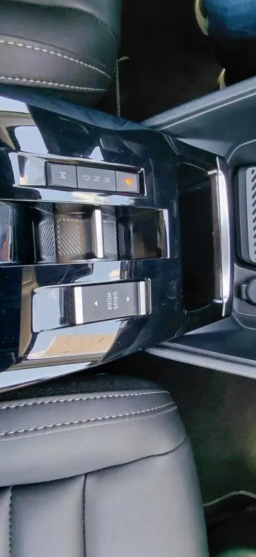 Vue plongeante sur la console centrale noire brillante du Citroën C4 X hybride 2025 avec commandes boîte auto et mode de conduite.