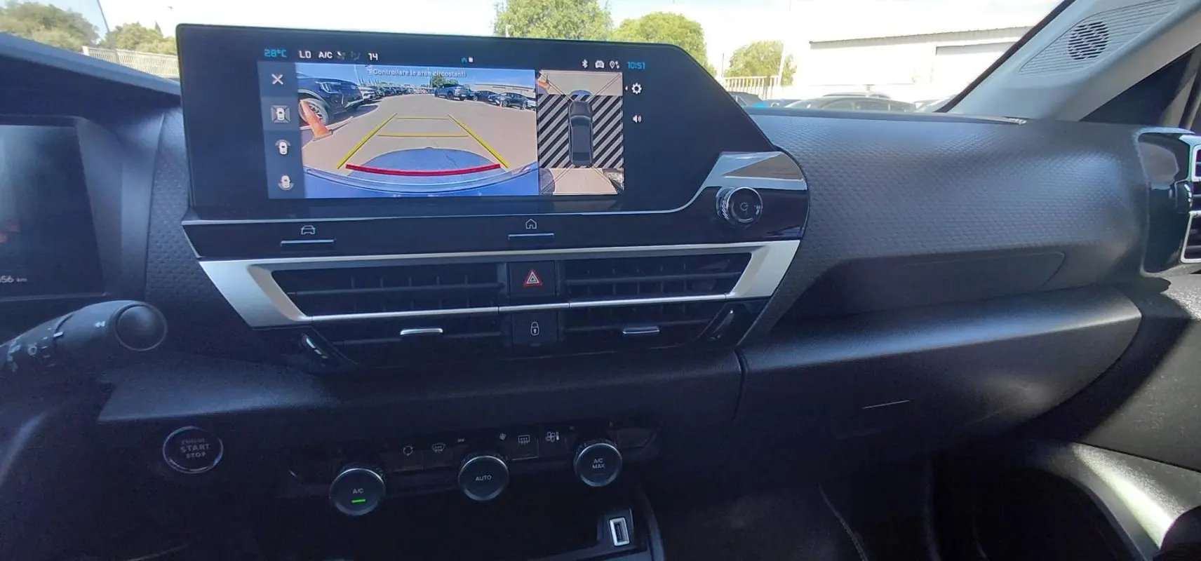 Vue intérieure du tableau de bord du Citroën C4 X noir 2025, avec écran tactile affichant la caméra de recul et commandes climatisation.