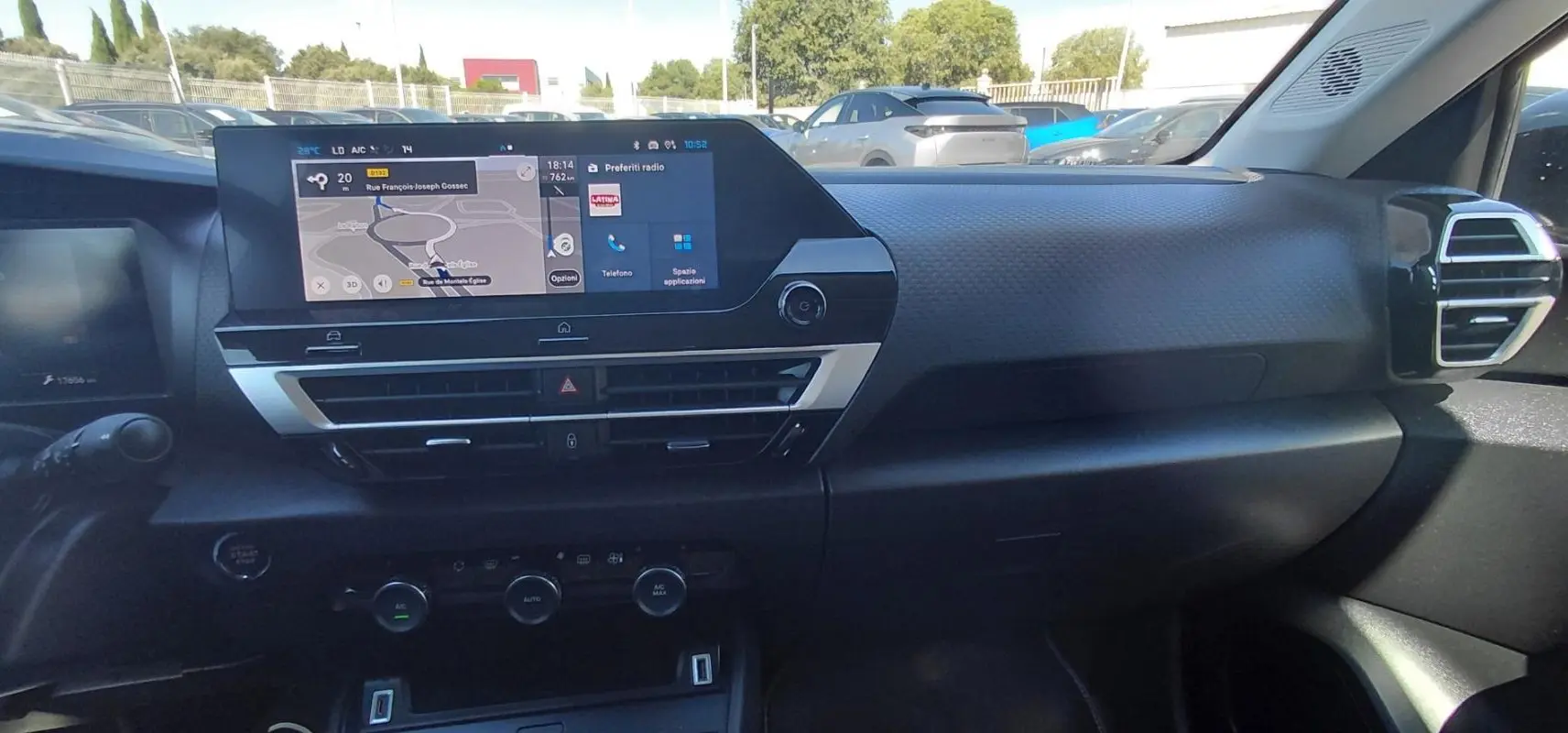 Vue intérieure du tableau de bord de la Citroën C4 X hybride 2025 avec écran tactile et commandes de climatisation.