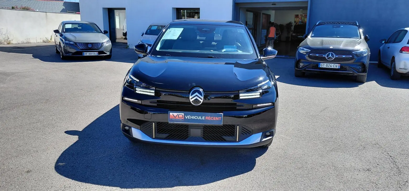 Vue avant d'une Citroën C4 X noire 2025 avec calandre distinctive et phares LED allumés.