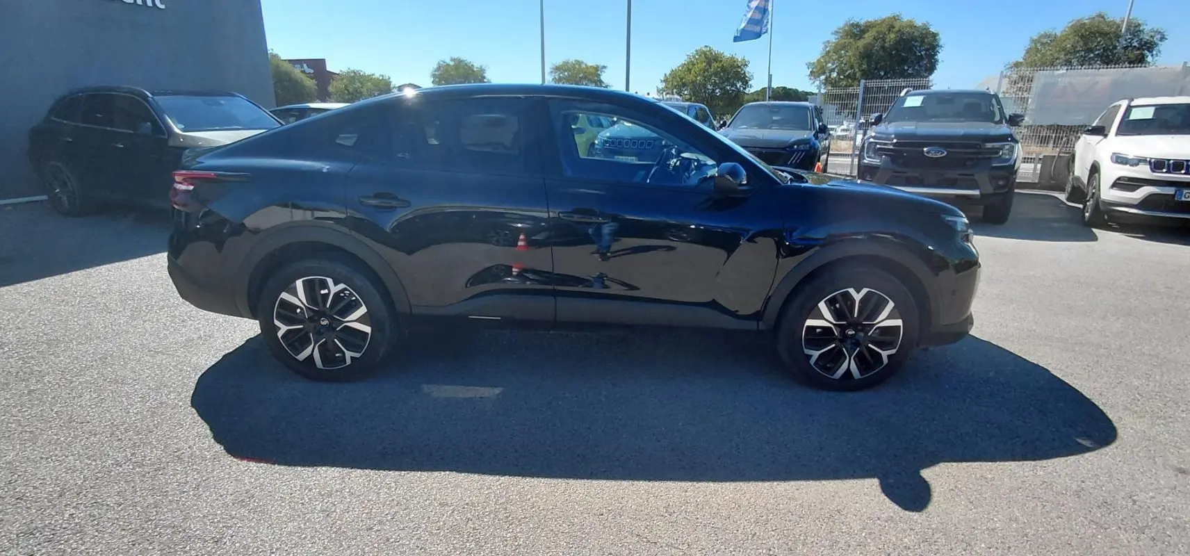 Profil côté gauche d'une Citroën C4 X noire 2025 avec jantes alliage 17 pouces, toit ouvrant panoramique visible.