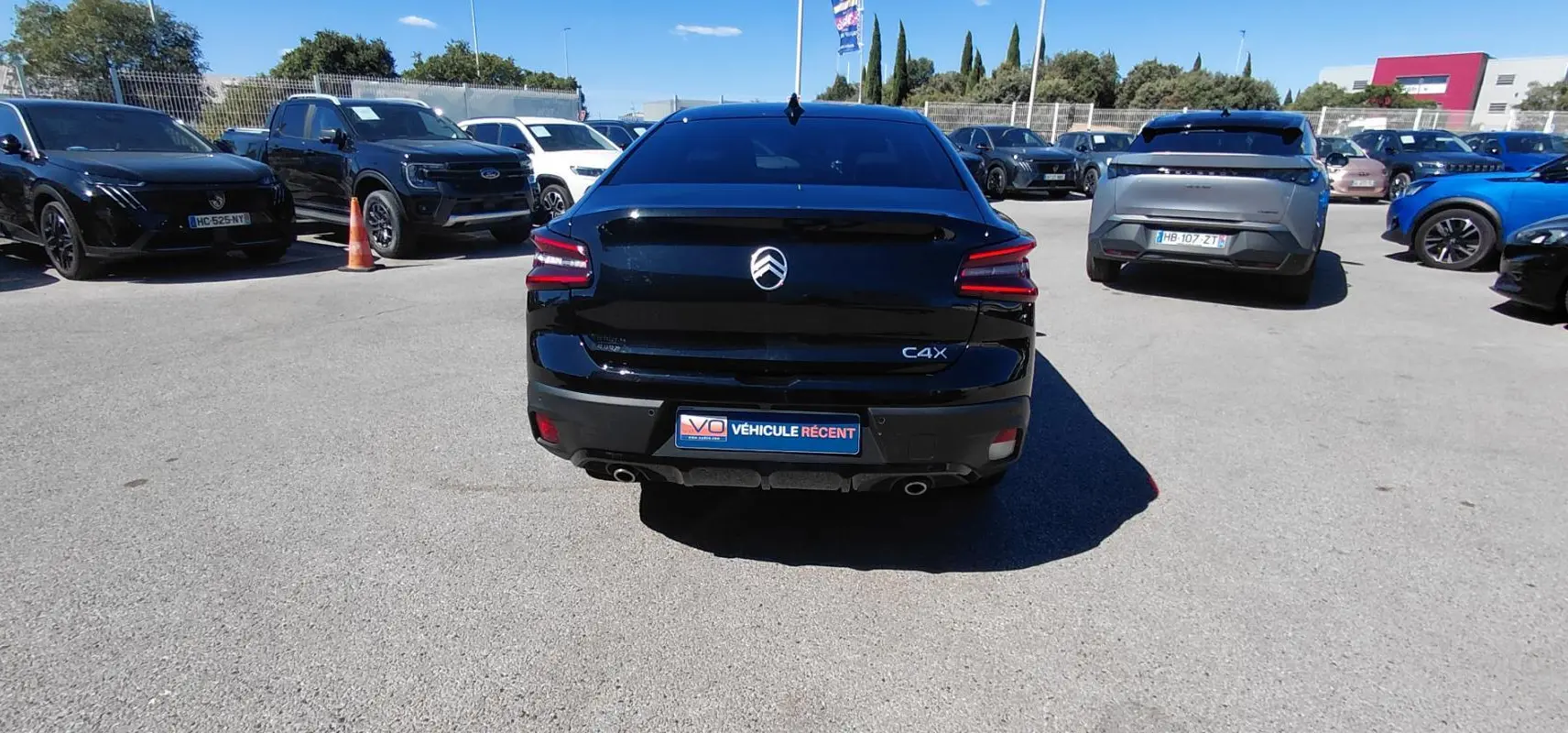 Vue arrière d'une Citroën C4 X noire 2025 avec feux LED et double sortie d'échappement visible sur parking.