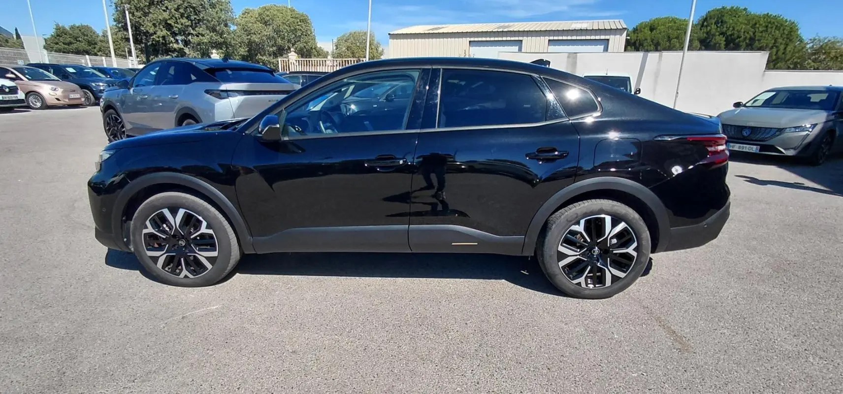Profil côté gauche de la Citroën C4 X noire 2025 avec jantes alliage 17 pouces, toit ouvrant panoramique visible.