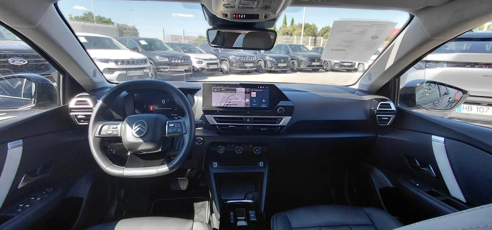 Vue intérieure avant du Citroën C4 X noir 2025, mettant en valeur le tableau de bord digital et le volant cuir.