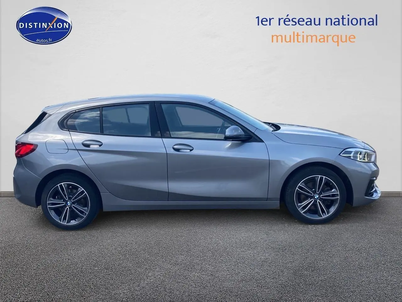 Profil côté gauche d'une BMW Série 1 gris foncé avec jantes alliage 17 pouces et phares LED allumés.