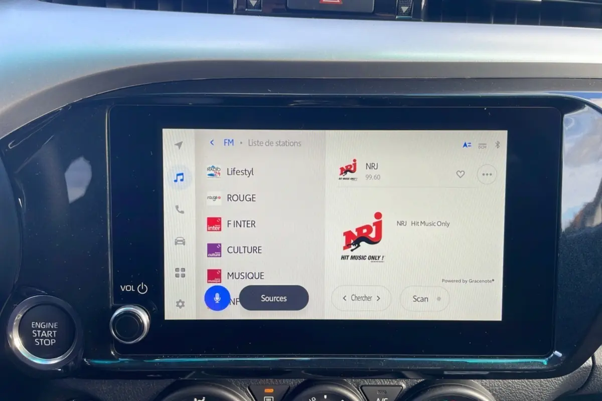 Écran tactile multimédia allumé du Toyota Hilux 2025, avec bouton moteur et commandes audio visibles.