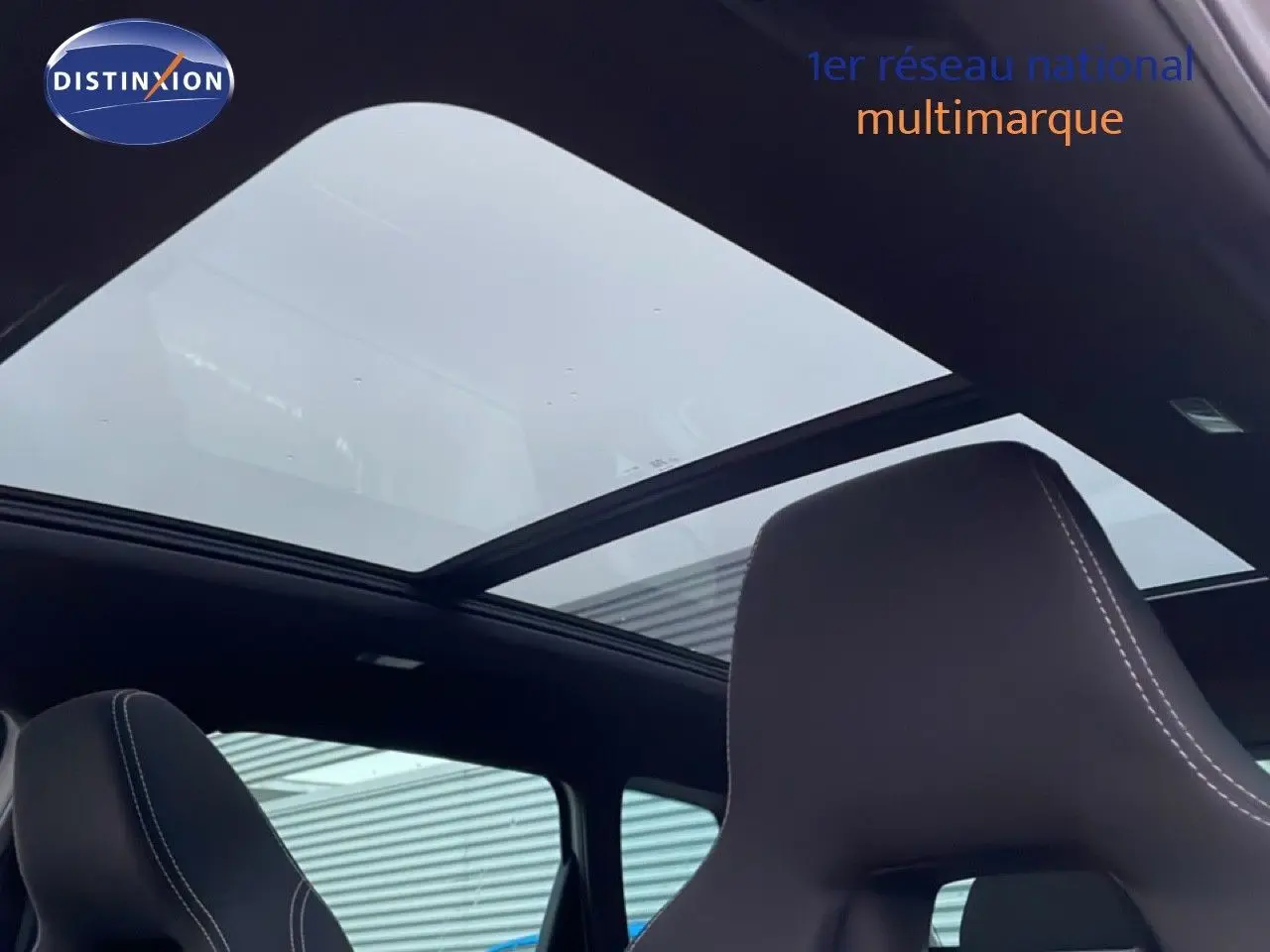 Toit panoramique ouvert et sièges avant en cuir noir dans un Skoda Karoq gris argent 2025, vue intérieure.