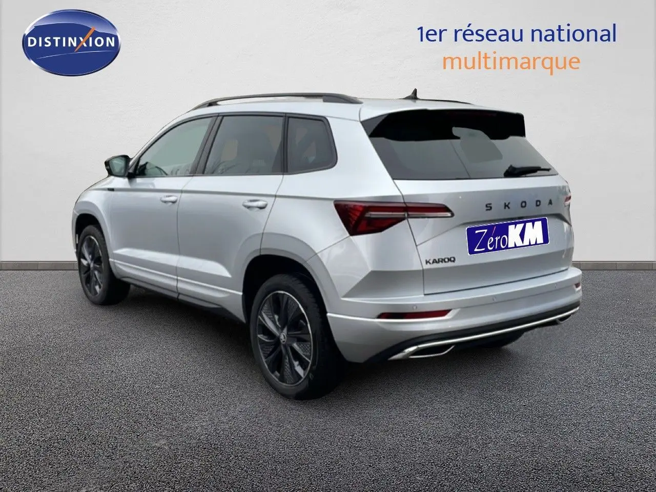 Vue 3/4 arrière droite d’un Skoda Karoq gris argent métallisé avec jantes bi-ton et feux LED distinctifs.