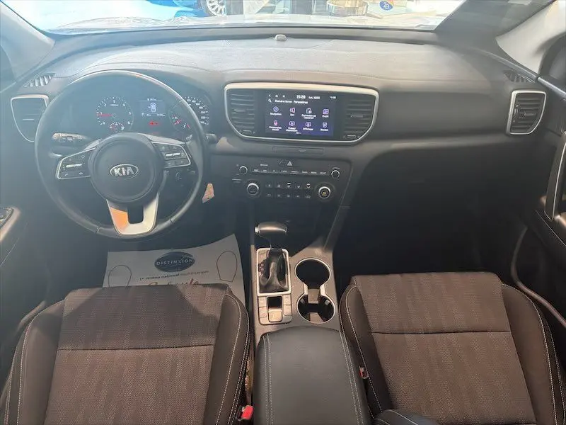 Vue intérieure avant du Kia Sportage 2021, tableau de bord noir avec écran tactile central et volant multifonction.