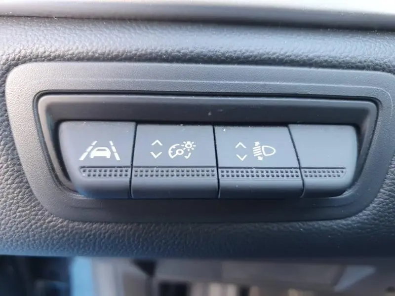 Gros plan sur les boutons de réglage d'assistance à la conduite dans un Renault Captur 2023, intérieur noir.