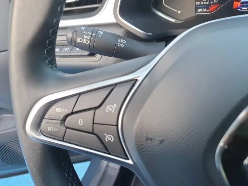 Gros plan sur les commandes multifonctions du volant noir du Renault Captur 2023, avec levier de clignotant en arrière-plan.
