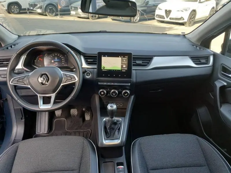 Vue intérieure avant du Renault Captur 2023 avec tableau de bord noir, volant multifonction et écran tactile central.