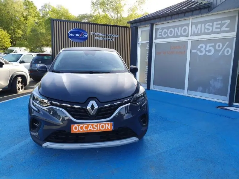 Vue avant d'un Renault Captur 2023 bleu marine fumé avec calandre chromée et plaque "OCCASION" orange visible.
