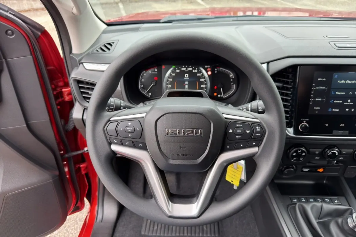 Vue intérieure centrée sur le volant multifonctions noir de l'Isuzu D-MAX 2026 avec tableau de bord et écran tactile.