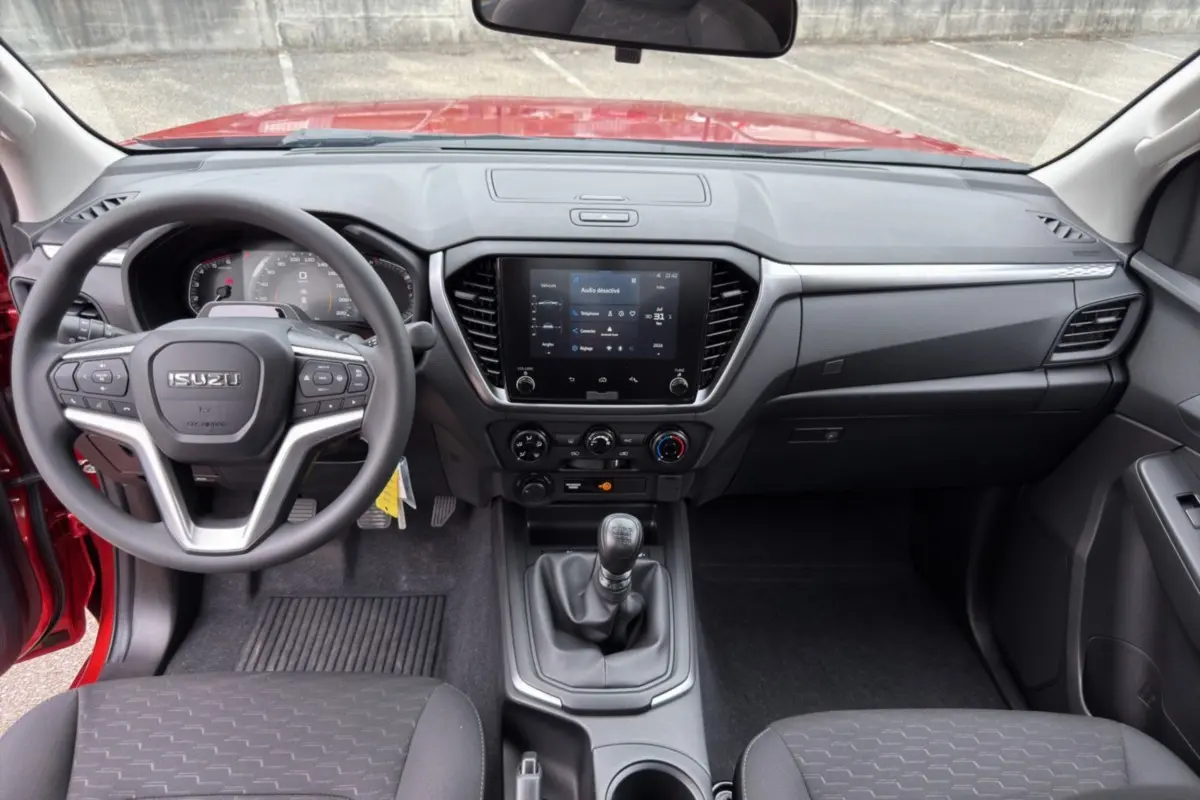 Vue intérieure avant de l'Isuzu D-MAX 2026 orange Namibu, volant multifonctions et écran tactile central visible.