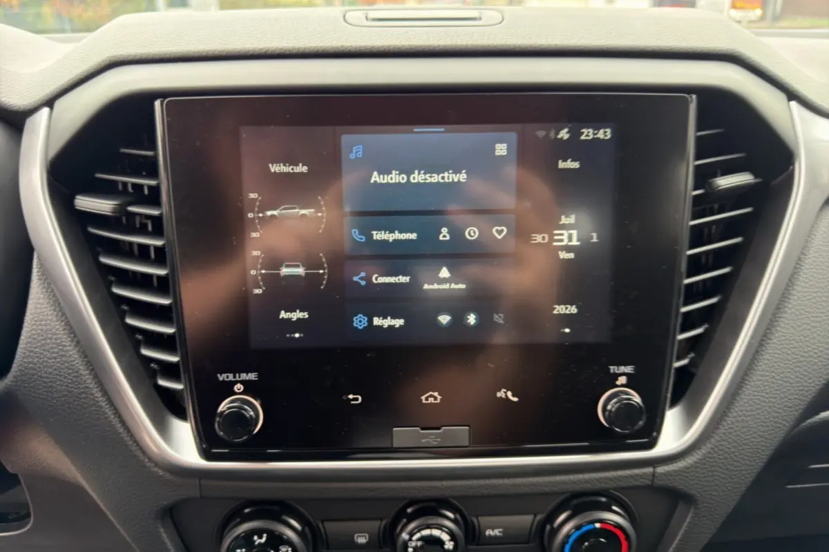 Écran tactile central de l’Isuzu D-MAX 2026 affichant le menu audio et connectivité, entouré de commandes de climatisation.