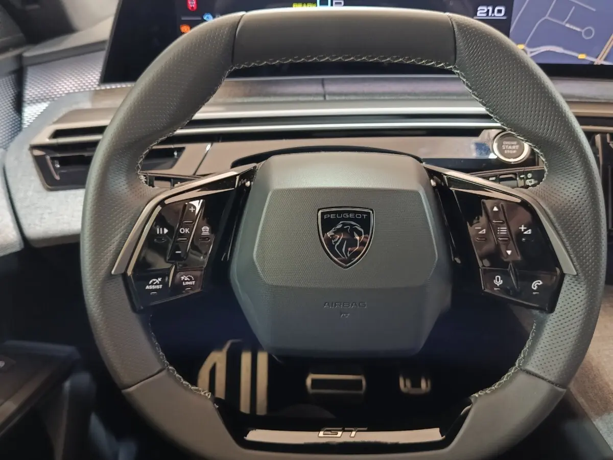 Vue rapprochée du volant cuir noir du Peugeot 5008 1.6 PHEV GT avec commandes multifonctions et logo central.