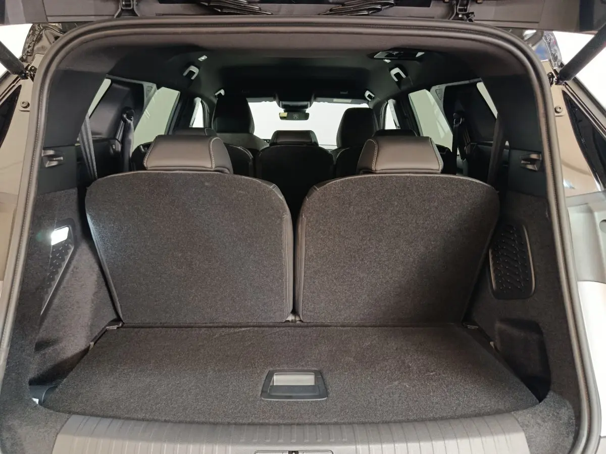 Coffre ouvert vu de l'arrière d'un Peugeot 5008 gris clair, sièges de troisième rangée relevés.