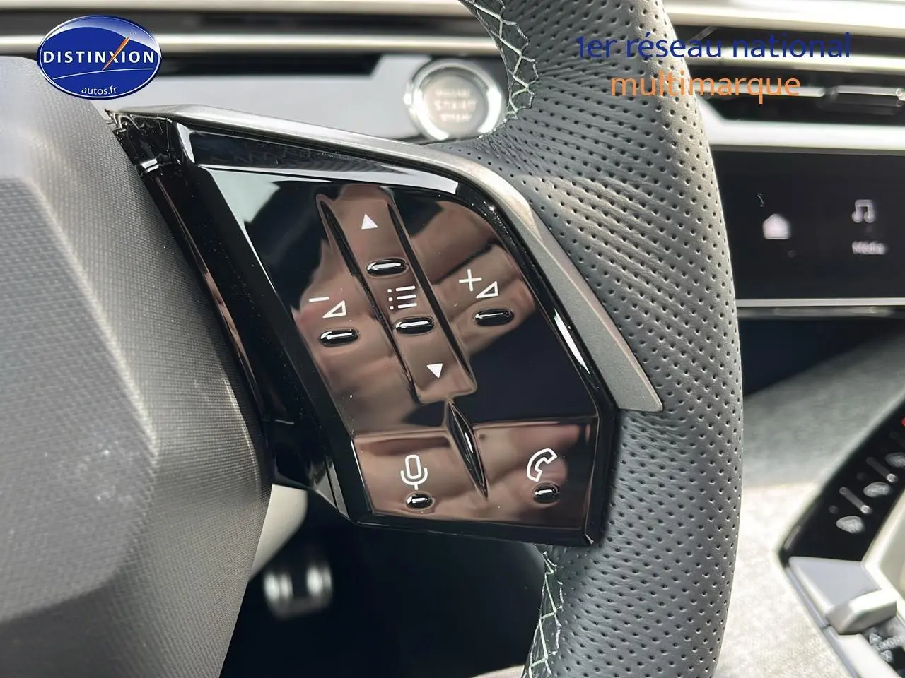 Gros plan sur les commandes au volant en cuir perforé du Peugeot 3008 gris hybride, avec boutons multifonctions et micro.