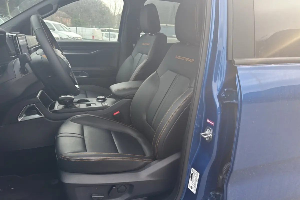 Vue intérieure côté conducteur du Ford Ranger Wildtrak bleu lightning, sièges cuir noirs avec surpiqûres orange et logo brodé.