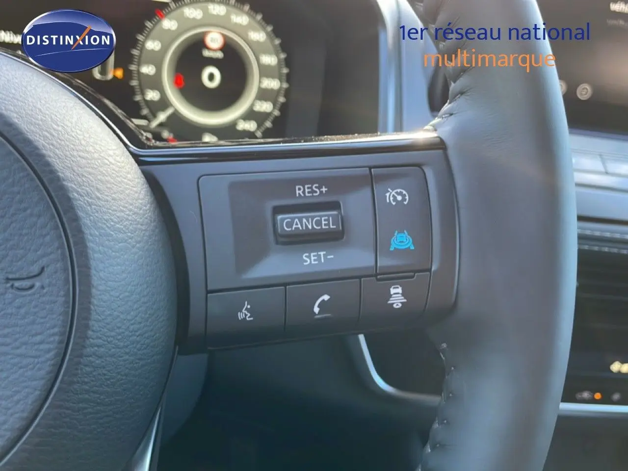 Gros plan sur le volant du Nissan Qashqai gris argile, avec commandes de régulateur de vitesse et tableau de bord numérique en arrière-plan.