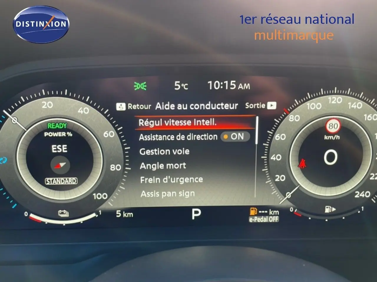Tableau de bord numérique du Nissan Qashqai gris argile, affichant l’aide au conducteur et la vitesse à 0 km/h.