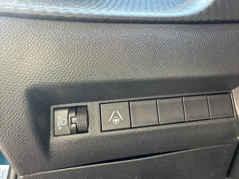 Détail des commandes intérieures noires sur la gauche du tableau de bord du Peugeot 2008 hybride 2025.